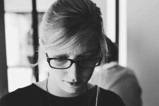 Black and white portrait of a young women wearing glasses and looking down.