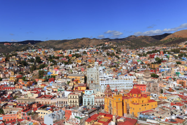Photo of the city of Guanajuato in Mexico. Multi colored buildings and houses with the mountain behind.