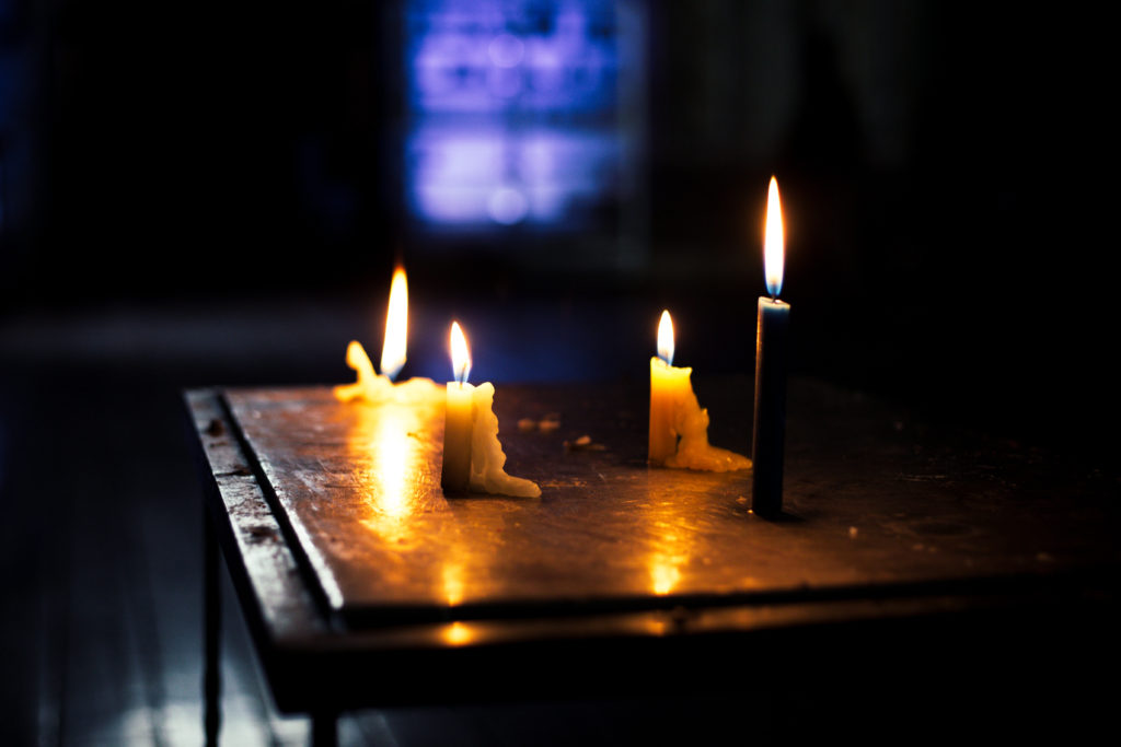 Candle light in an Ecuadorian church. Dark photo with the candle lights in the foreground and a blue / purple stained glass in the background