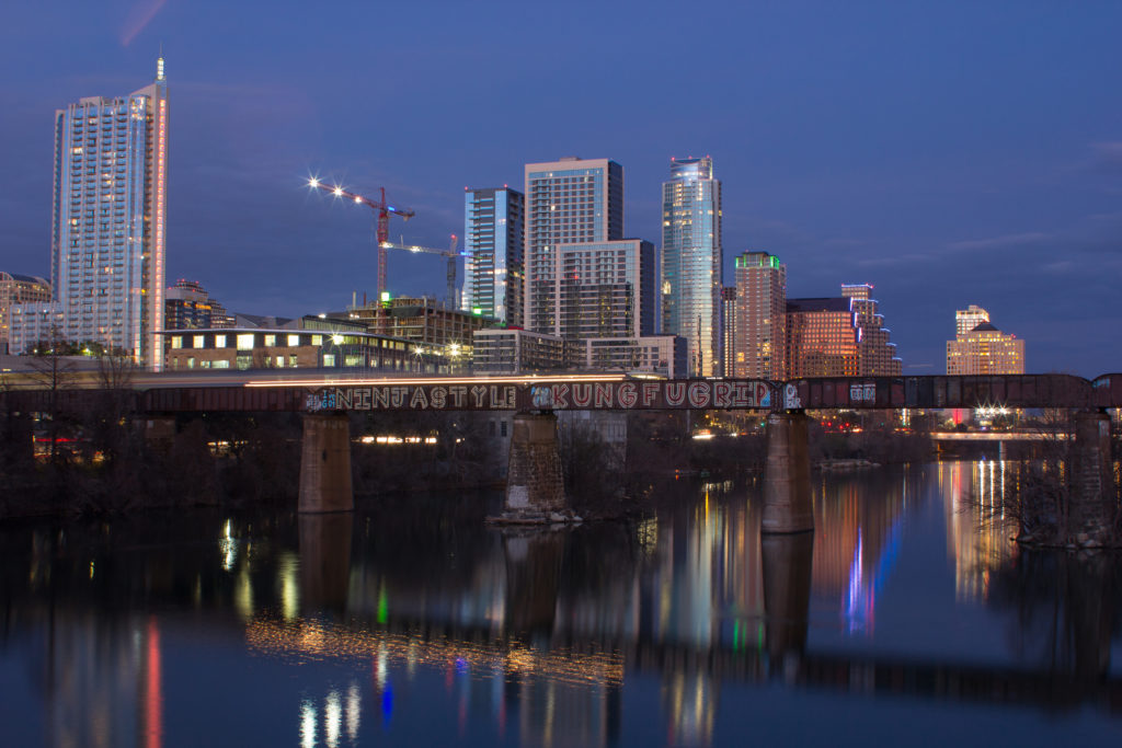 Night view of Austin, Texas downtown with building in the background and a bridge in the foreground